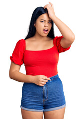 Obraz premium Young beautiful asian girl wearing casual clothes surprised with hand on head for mistake, remember error. forgot, bad memory concept.