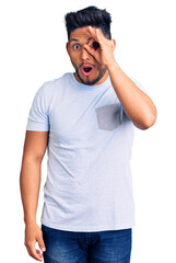 Fototapeta premium Handsome latin american young man wearing casual clothes doing ok gesture shocked with surprised face, eye looking through fingers. unbelieving expression.