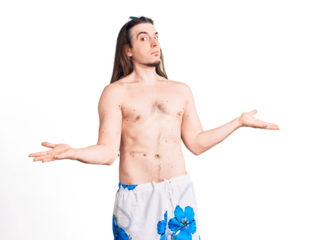 Young adult man with long hair wearing swimwear shirtless clueless and confused expression with arms and hands raised. doubt concept.