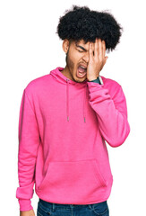 Young african american man with afro hair wearing casual pink sweatshirt yawning tired covering half face, eye and mouth with hand. face hurts in pain.
