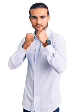 Young handsome man wearing business clothes ready to fight with fist defense gesture, angry and upset face, afraid of problem