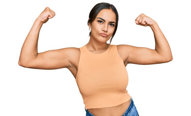 Young brunette woman wearing casual clothes showing arms muscles smiling proud. fitness concept.