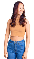 Fototapeta premium Young beautiful chinese girl wearing casual clothes looking away to side with smile on face, natural expression. laughing confident.