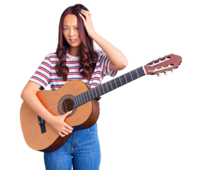 Young beautiful chinese girl playing classical guitar stressed and frustrated with hand on head, surprised and angry face