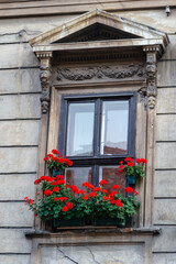 Fototapeta na wymiar Window with a decorative baroque facade. Window with a decorative baroque facade, decorated with red flowers.