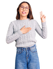 Young beautiful chinese girl wearing casual clothes smiling swearing with hand on chest and fingers...