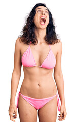Obraz premium Young beautiful hispanic woman wearing bikini angry and mad screaming frustrated and furious, shouting with anger. rage and aggressive concept.