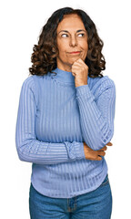 Middle age hispanic woman wearing casual clothes serious face thinking about question with hand on...