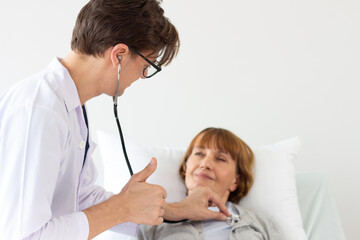 the doctor is examining the patient in the hospital. white male doctor examining an elderly female white patient.