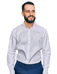 Young man with beard wearing business shirt looking away to side with smile on face, natural expression. laughing confident.
