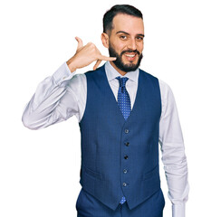 Young man with beard wearing business vest smiling doing phone gesture with hand and fingers like talking on the telephone. communicating concepts.