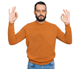 Young man with beard wearing casual winter sweater relax and smiling with eyes closed doing meditation gesture with fingers. yoga concept.
