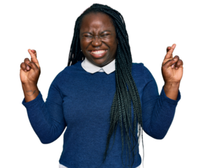 Young black woman with braids wearing casual clothes gesturing finger crossed smiling with hope and eyes closed. luck and superstitious concept.
