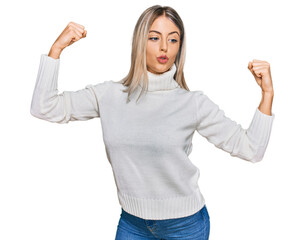Obraz premium Beautiful blonde woman wearing casual turtleneck sweater showing arms muscles smiling proud. fitness concept.
