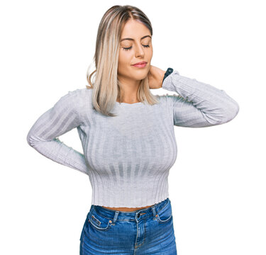Beautiful blonde woman wearing casual clothes suffering of neck ache injury, touching neck with hand, muscular pain