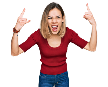 Young blonde girl wearing casual clothes shouting with crazy expression doing rock symbol with hands up. music star. heavy music concept.