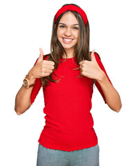 Young brunette woman wearing casual clothes success sign doing positive gesture with hand, thumbs up smiling and happy. cheerful expression and winner gesture.