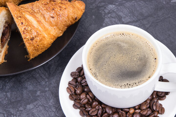 White cup of coffee and fresh croissant with chocolate for breakfast