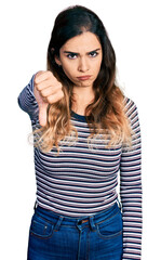 Beautiful hispanic woman wearing casual striped shirt looking unhappy and angry showing rejection and negative with thumbs down gesture. bad expression.