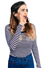 Beautiful hispanic woman wearing casual striped shirt shouting and screaming loud to side with hand on mouth. communication concept.