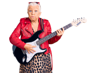 Senior beautiful woman with blue eyes and grey hair wearing a modern look playing electric guitar puffing cheeks with funny face. mouth inflated with air, crazy expression.