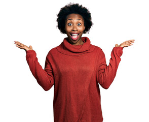 African american woman with afro hair wearing turtleneck sweater celebrating victory with happy smile and winner expression with raised hands