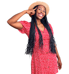 Young african american woman wearing summer hat smiling pointing to head with one finger, great idea or thought, good memory