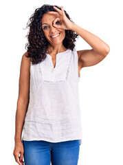 Middle age beautiful woman wearing casual sleeveless t shirt smiling happy doing ok sign with hand on eye looking through fingers