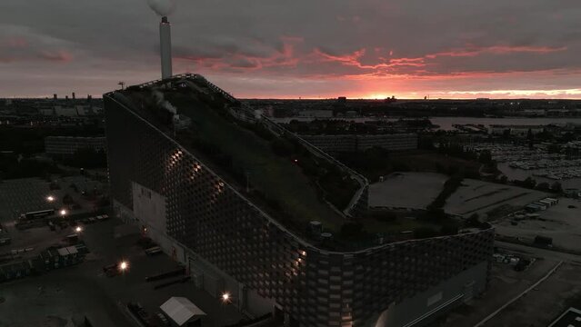 Aerial view of the Amager Bakke, Copenhill Waste-to-Energy Power Plant with green ski slopes with slides and kickers at sunset. Green eco energy plant.