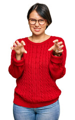 Young beautiful hispanic woman with short hair wearing casual sweater and glasses smiling funny...