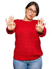 Young beautiful hispanic woman with short hair wearing casual sweater and glasses doing stop gesture with hands palms, angry and frustration expression