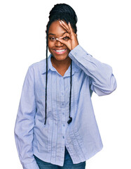 Young african american woman wearing casual clothes doing ok gesture with hand smiling, eye looking through fingers with happy face.