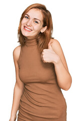 Young caucasian woman wearing casual clothes doing happy thumbs up gesture with hand. approving expression looking at the camera showing success.