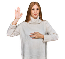 Young irish woman wearing casual winter sweater swearing with hand on chest and open palm, making a...