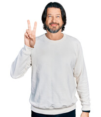 Naklejka premium Middle age caucasian man wearing casual clothes showing and pointing up with fingers number two while smiling confident and happy.