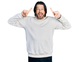 Middle age caucasian man wearing casual clothes smiling amazed and surprised and pointing up with fingers and raised arms.