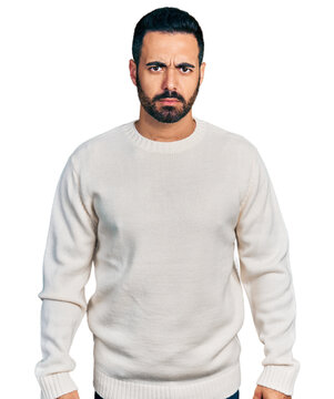 Young hispanic man with beard wearing casual white sweater skeptic and nervous, frowning upset because of problem. negative person.