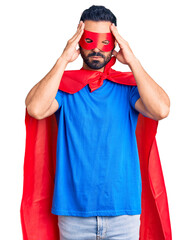Young hispanic man wearing super hero costume suffering from headache desperate and stressed because pain and migraine. hands on head.