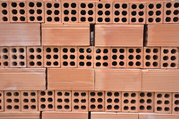 Background of baked clay bricks. Six-hole bricks stacked evenly. Construction materials.
