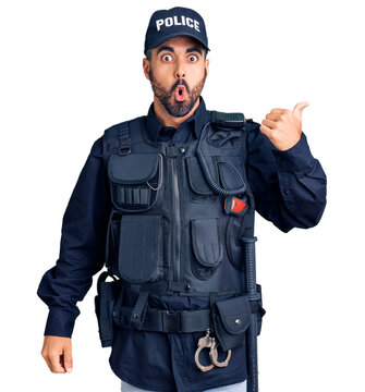 Young hispanic man wearing police uniform surprised pointing with hand finger to the side, open mouth amazed expression.