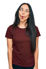 Fototapeta premium Young hispanic girl wearing casual t shirt making fish face with lips, crazy and comical gesture. funny expression.