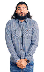 Young arab man wearing casual clothes puffing cheeks with funny face. mouth inflated with air, crazy expression.