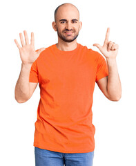 Young handsome man wering casual t shirt showing and pointing up with fingers number seven while smiling confident and happy.