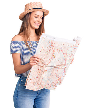 Young beautiful girl wearing hat holding city map looking positive and happy standing and smiling with a confident smile showing teeth
