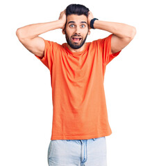 Young handsome man with beard wearing casual t-shirt crazy and scared with hands on head, afraid and surprised of shock with open mouth