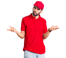 Young handsome man with beard wearing delivery uniform clueless and confused with open arms, no idea concept.