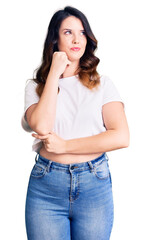 Beautiful young brunette woman wearing casual clothes serious face thinking about question with hand on chin, thoughtful about confusing idea