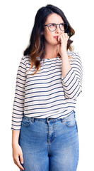 Fototapeta premium Beautiful young brunette woman wearing casual clothes and glasses looking stressed and nervous with hands on mouth biting nails. anxiety problem.