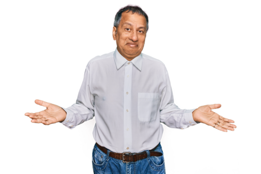 Middle age indian man wearing casual white shirt clueless and confused expression with arms and hands raised. doubt concept.