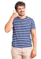 Young handsome man with curly hair wearing casual clothes smiling doing phone gesture with hand and fingers like talking on the telephone. communicating concepts.